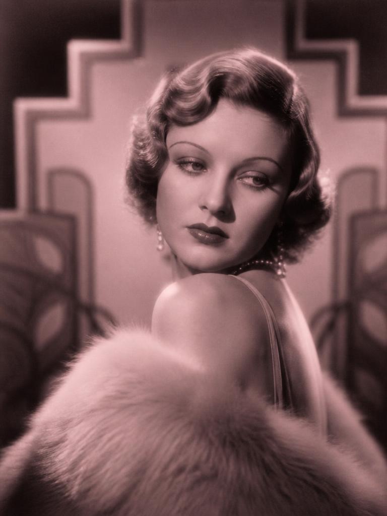 1930s film star in a fur stole and pearls against an art deco backdrop